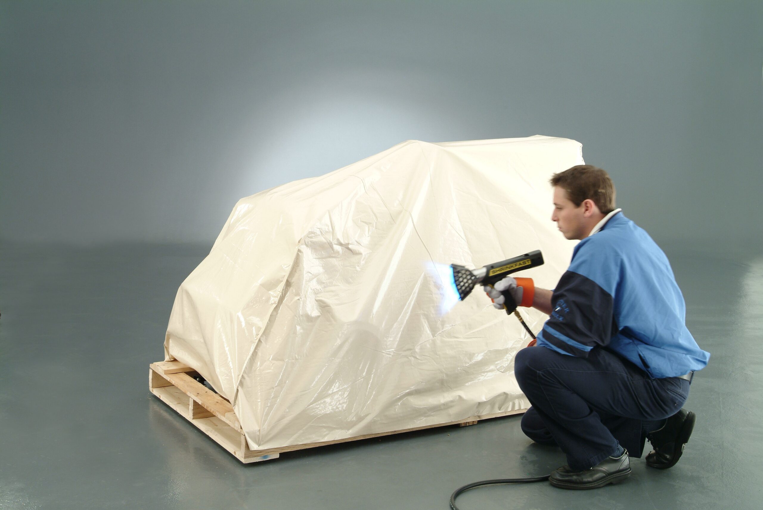 Man Heat Shrinking a Cover to a Tractor on a Pallet
