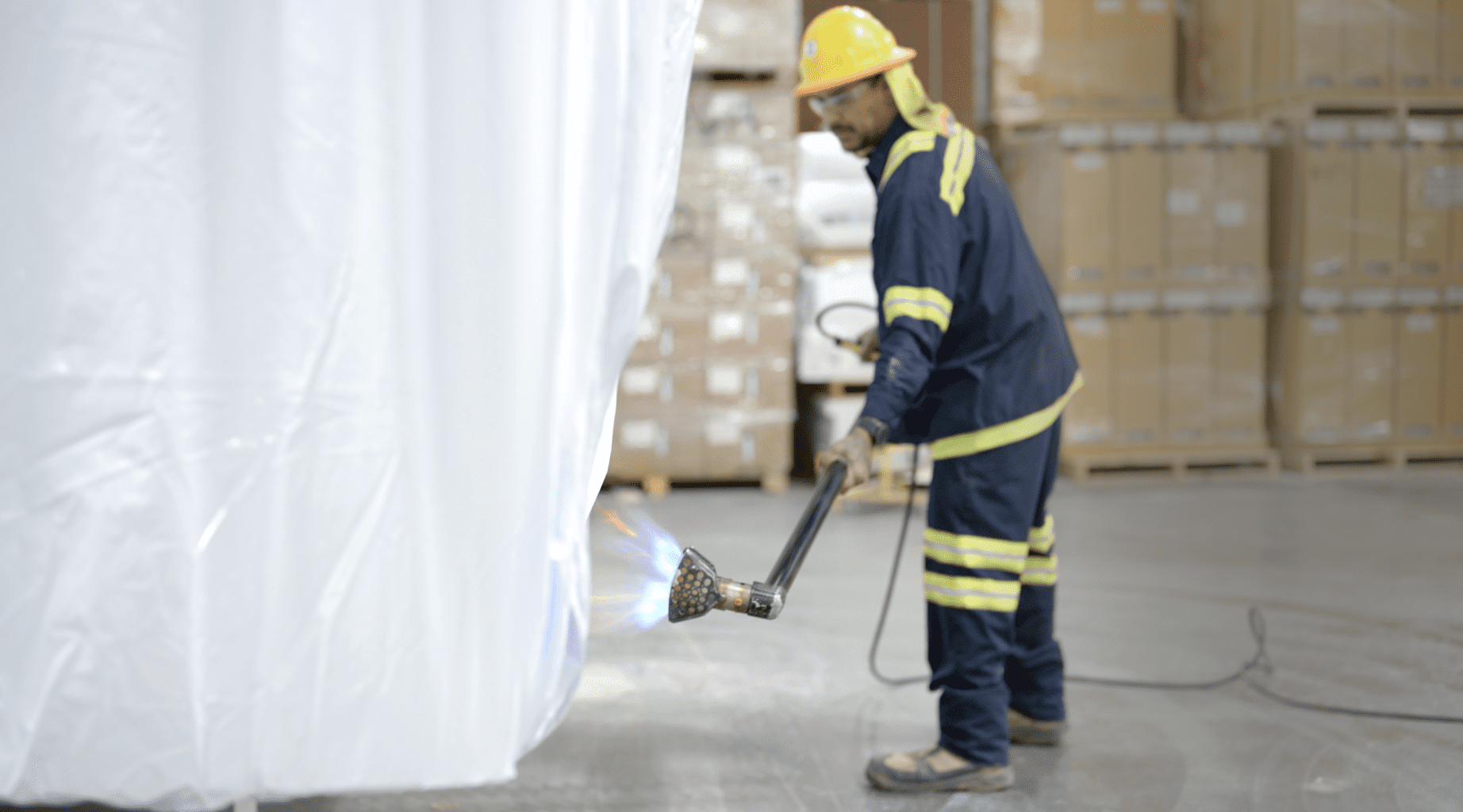 Worker Using Heat Gun to Shrink Cover to Size