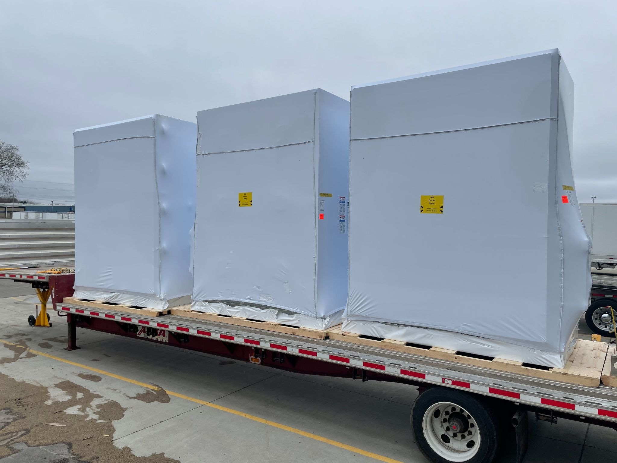 three containers wrapped in transhield covers on a pallet