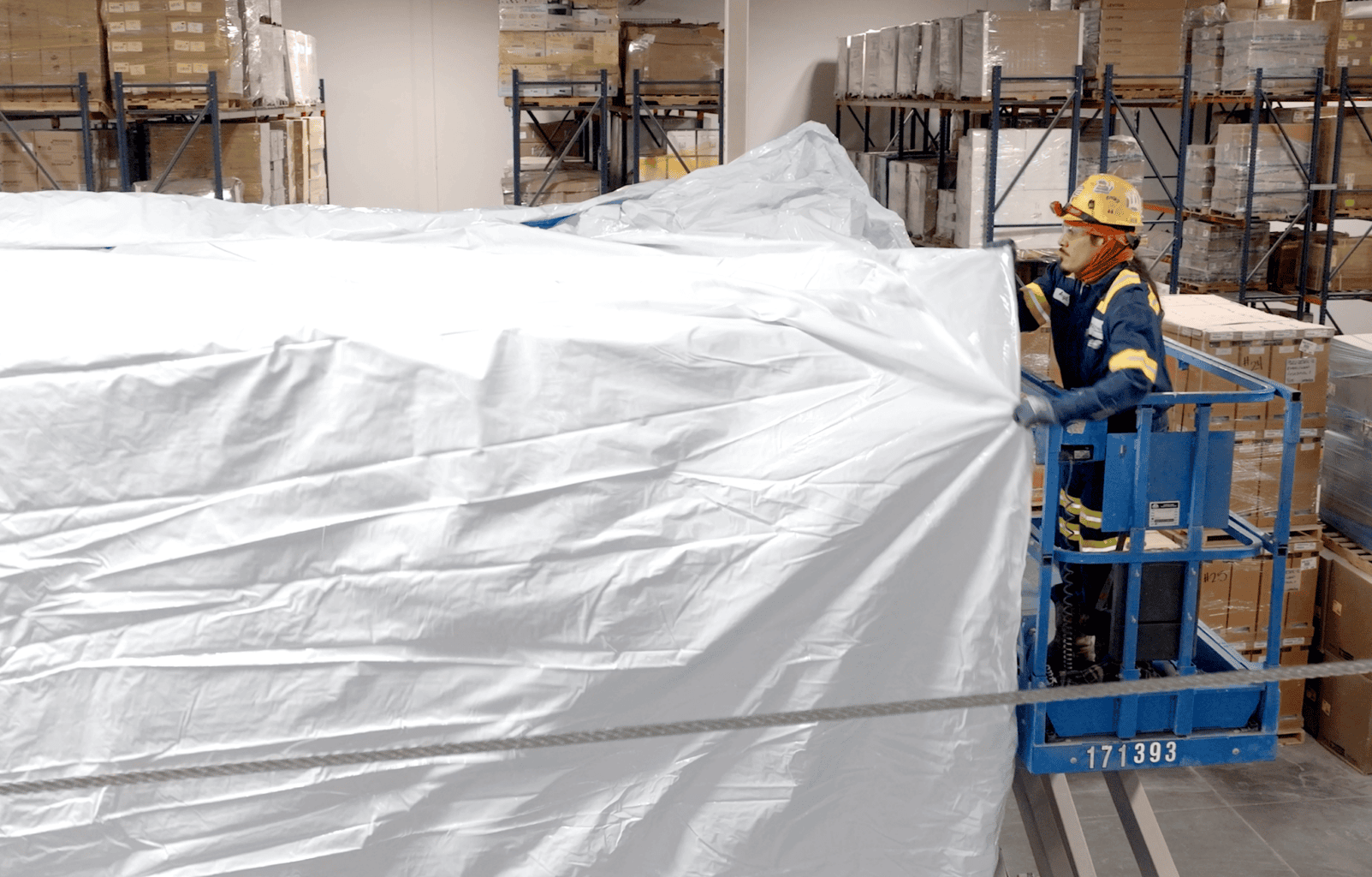 employee pullling on a transhield custom cover over a piece of equipment